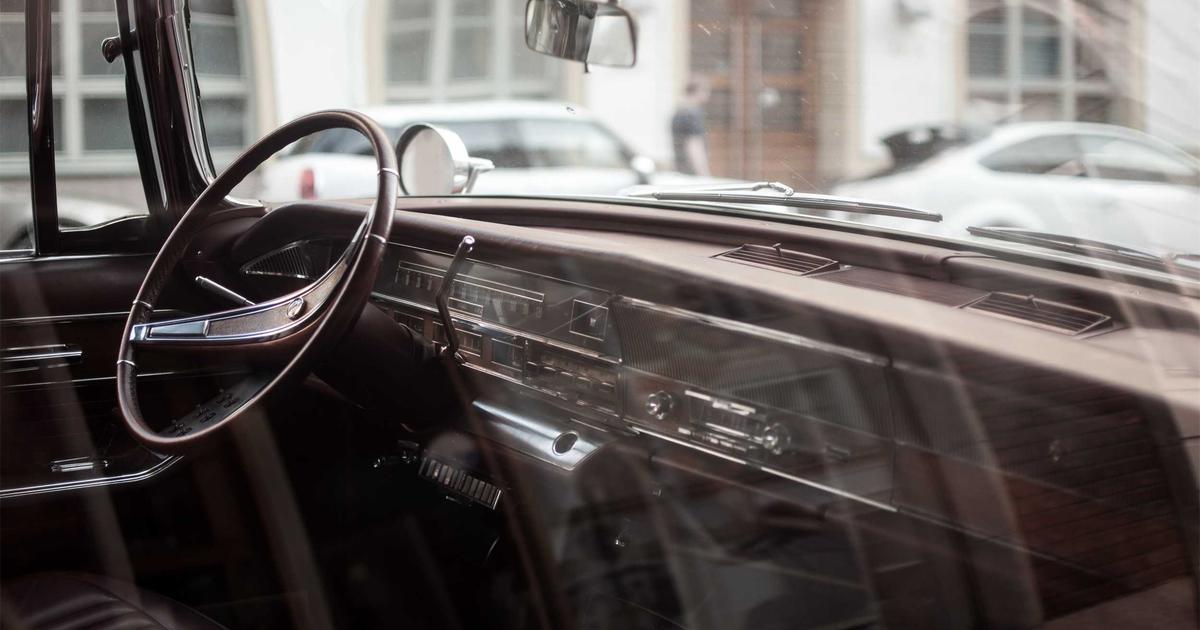 A woman applying natural skincare products at home, surrounded by colorful jars and a mirror in a bright bathroom.